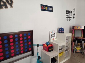 Una stanza con una macchina da flipper, un gioco Pac-Man e un cartello con scritto 'GAME OVER'.