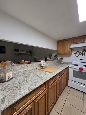 A modern kitchen with granite countertops, wooden cabinets, a built-in oven, and a coffee station. - Family Safe NOLA-Area : MSY Airport : GAME ROOM : FREE Park'n : 3 BEDS (Destrehan)