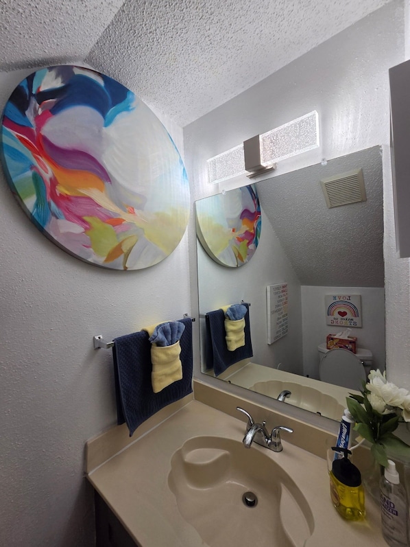 A bathroom with a beige sink, a mirror, and two towels hanging on hooks. - Family Safe NOLA-Area : MSY Airport : GAME ROOM : FREE Park'n : 3 BEDS (Destrehan)