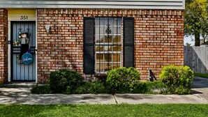 A two-story building with a brick facade, a blue door with a 'Welcome' sign, and a number '351' above the door. - Family Safe NOLA-Area : MSY Airport : GAME ROOM : FREE Park'n : 3 BEDS (Destrehan)