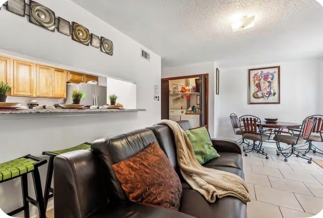 Een woonkamer met een bank, een salontafel en een eethoek met stoelen en een tafel.