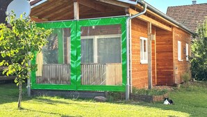 Een houten huis met een overdekte veranda en een groene deur.