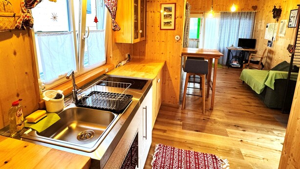 Een houten interieur met een keukenhoek, een eethoek en een zithoek.