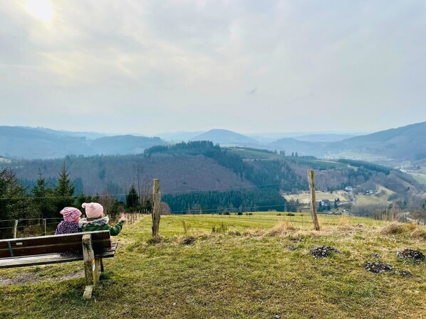A bench overlooking a mountainous landscape with a clear view of distant hills and a valley.