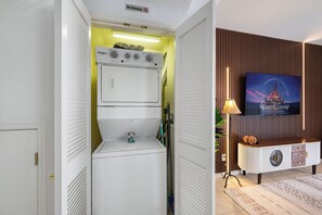 A compact room with a washer and dryer, a television on a wooden cabinet, and a 'No Smoking' sign. - THEMED 4 BR Coral Cay GEM w/Lake view-10 min to Disney-Free BBQ-Free resort (Kissimmee)