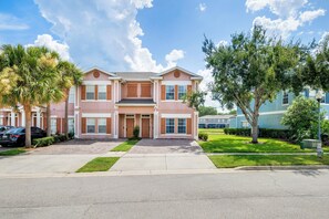 A two-story house with a front porch, a driveway, and a lawn. - THEMED 4 BR Coral Cay GEM w/Lake view-10 min to Disney-Free BBQ-Free resort (Kissimmee)