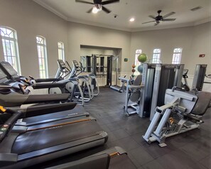 Une salle de sport équipée de tapis de course, de vélos elliptiques et d'appareils de musculation.