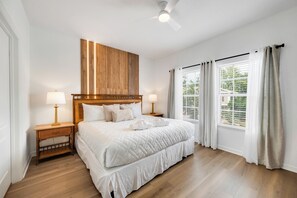 A hotel room with a large bed, two bedside tables, a ceiling fan, and a window with curtains. - THEMED 4 BR Coral Cay GEM w/Lake view-10 min to Disney-Free BBQ-Free resort (Kissimmee)