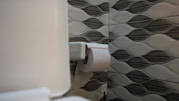 Un inodoro con un rollo de papel higiénico y una pared con diseño.