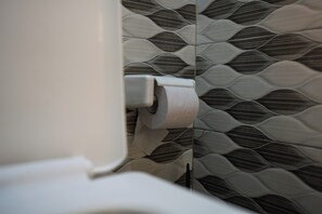 Un inodoro con un rollo de papel higiénico y una pared con diseño.