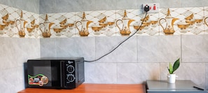 Un horno microondas sobre una encimera de madera, con un cable de alimentación conectado a un enchufe de pared.
