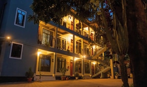 Un edificio de varios pisos con balcones, una escalera y plantas en macetas.