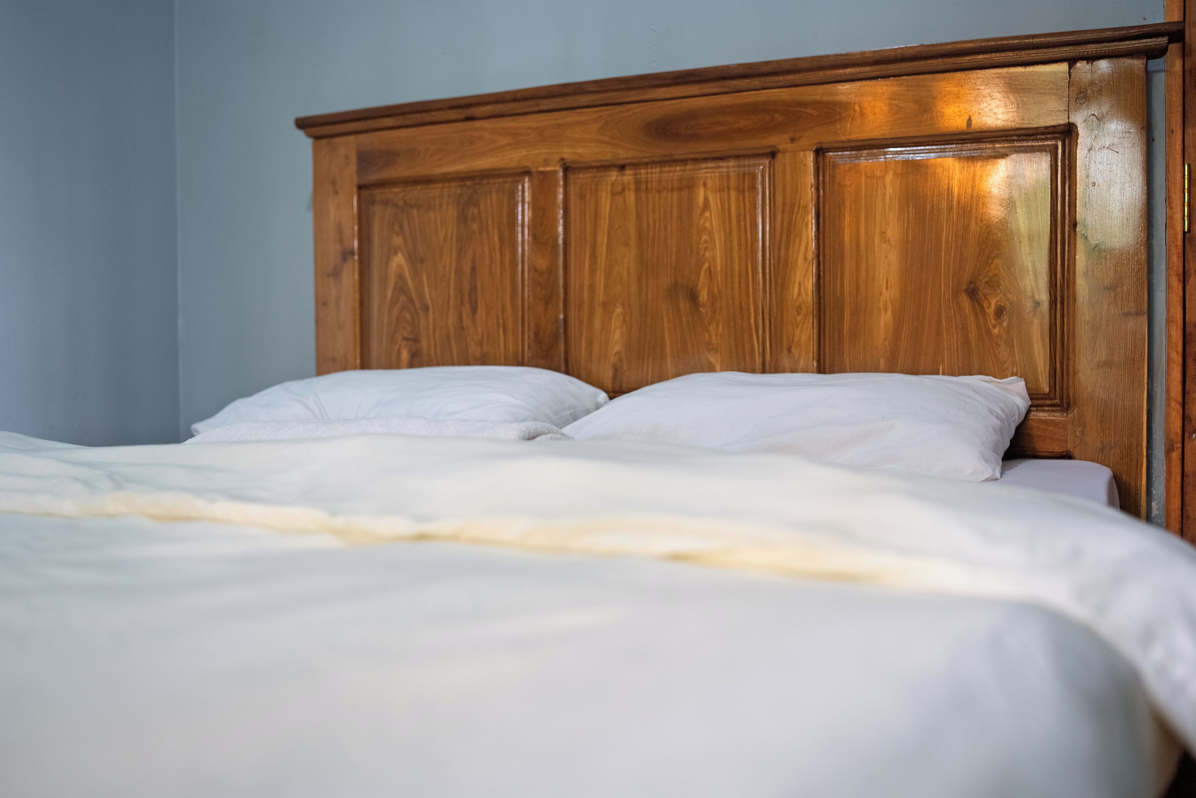 Una cama con cabecera de madera y ropa de cama blanca.