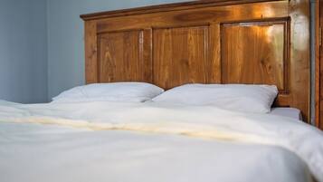 Una cama con cabecera de madera y ropa de cama blanca.