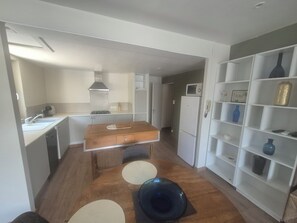 Een compacte keuken met een centraal eiland, witte kasten en een magnetron op het aanrecht.