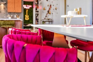 Une cuisine moderne avec un plan de travail blanc, des tabourets de bar rouges et un néon.