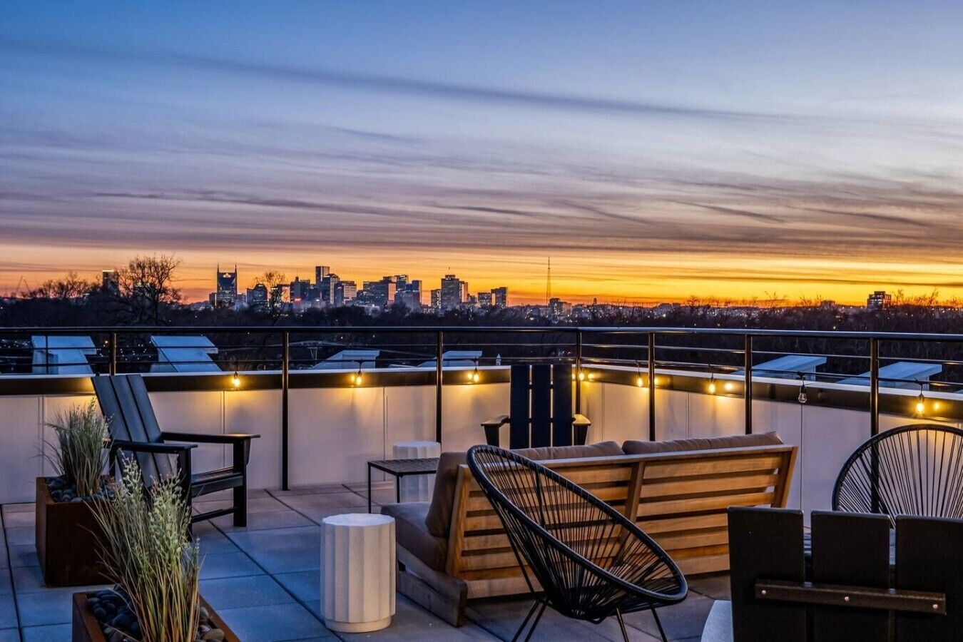 A rooftop terrace with seating, a city skyline view, and solar panels.