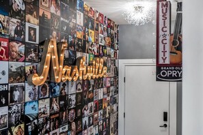 A wall filled with movie posters, a neon sign spelling 'Nashville,' and a 'Music City' sign. - The Nash Bash | Skyline Rooftop + Mins to Downtown (Nashville)