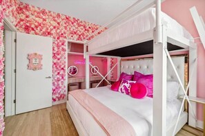 Ein Schlafzimmer mit Etagenbett, Schminktisch mit Spiegel und blumengemusterten Wand.