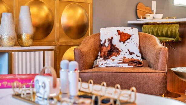 Ein modernes Wohnzimmer mit einem braunen Ledersofa, einem Zierkissen und einem Tablett mit Flaschen.