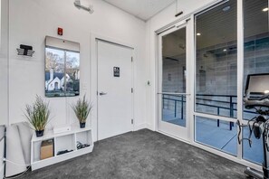 A clean, modern waiting area with a reception desk, a wheelchair-accessible restroom sign, and a large window with a view of the outside. - The Nash Bash | Skyline Rooftop + Mins to Downtown (Nashville)