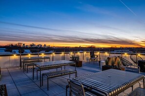Eine Dachterrasse mit Sitzgelegenheiten und einem Stadtblick bei Sonnenuntergang.