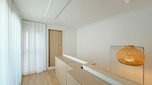 Une pièce moderne et minimaliste, avec un banc en bois, une porte et un luminaire suspendu.