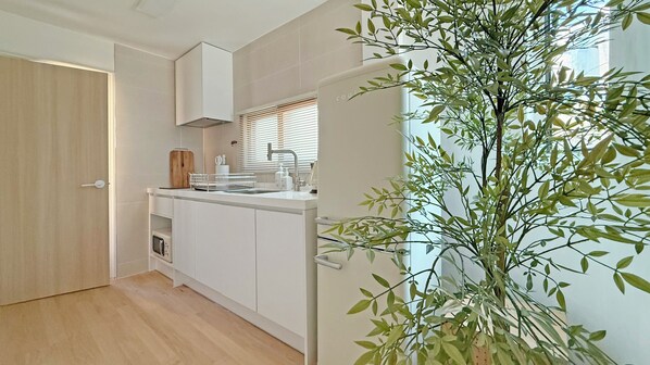 A modern kitchen with white cabinetry, a built-in oven, and a window with blinds.