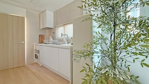 Une cuisine moderne avec des meubles blancs, un four encastré et une fenêtre équipée de stores.
