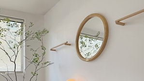 Une chambre à coucher avec un lit, une table de chevet, un miroir et une plante en pot.