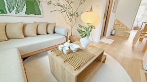 Un salon moderne avec un canapé, une table basse sur laquelle sont posées des théières, une lampe et un escalier.