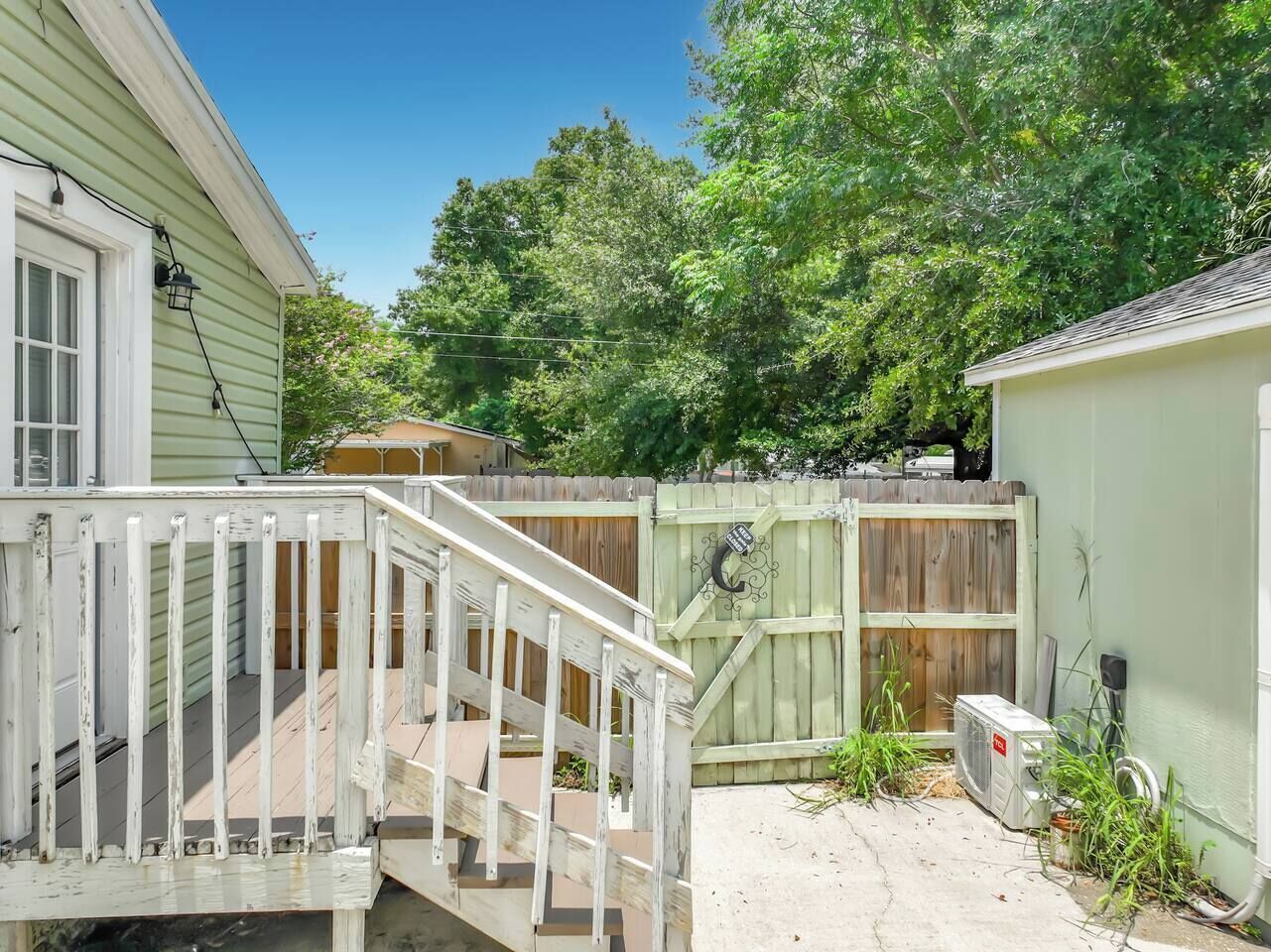 A residential backyard with a wooden deck, a fenced area, and a utility shed.