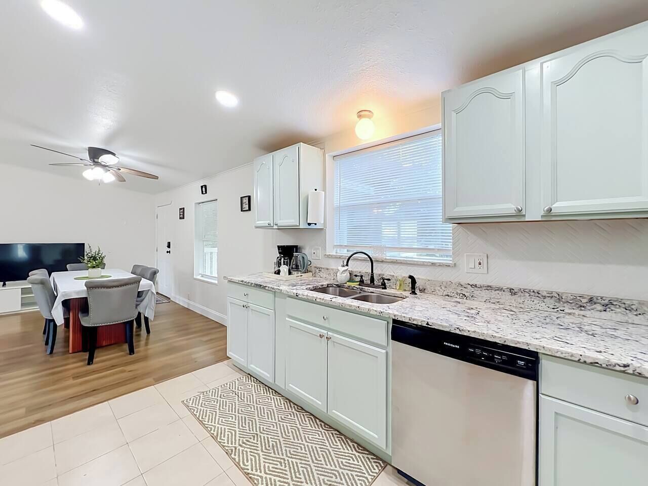 A modern kitchen with white cabinets, a granite countertop, and a built-in dishwasher.