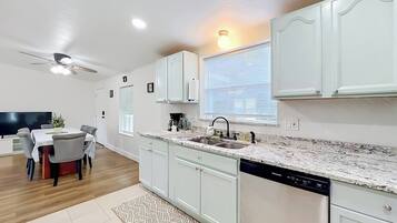 A modern kitchen with white cabinets, a granite countertop, and a built-in dishwasher.