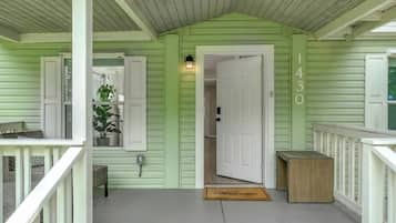 A porch with a green exterior, a white door, and a mailbox.