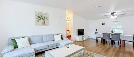 Una sala de estar moderna con un sofá, una mesa de centro y un comedor con sillas.