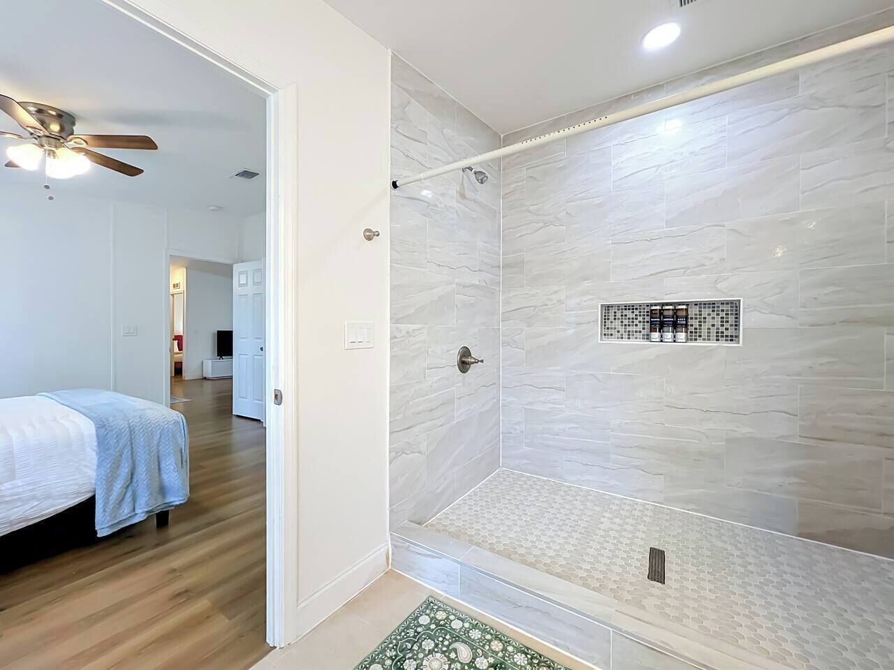 A modern bathroom with a shower, tiled walls, and a ceiling fan.