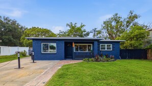 A single-story house with a blue exterior, a front door, and a small front yard with grass and plants. - 3-bedroom house in wonderful Winter Park with Big Fenced-In Back Yard! (Winter Park)