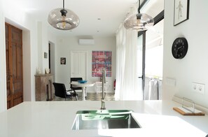 A modern kitchen with a central island, a dining area with a table and chairs, and a large window with curtains. - Casa art&co (Palma)