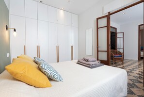 A bedroom with a bed, pillows, a mirror, and a door leading to another room. - Casa art&co (Palma)