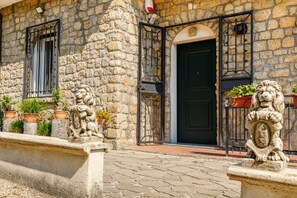 Un edificio de piedra con una puerta negra, una estatua de león y plantas en macetas.