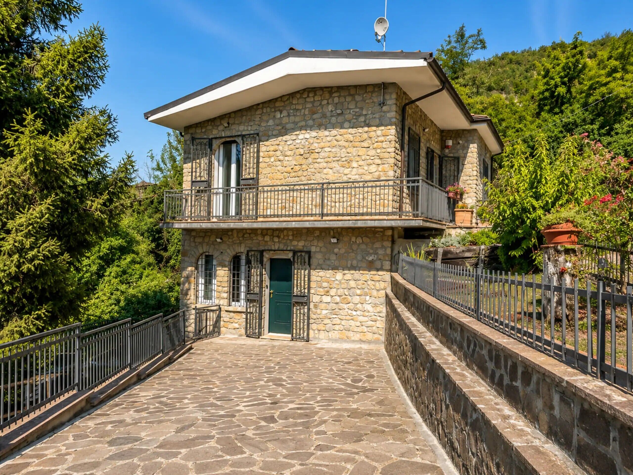 Un bâtiment en pierre doté d’un balcon, d’une porte et d’une antenne parabolique.
