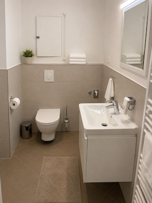 Ein modernes Badezimmer mit Toilette, Waschbecken und Spiegel.