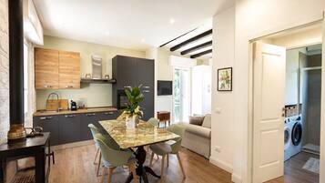 A modern kitchen with dark cabinets, a wooden dining table, and a built-in stove.