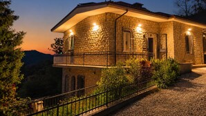 A stone building with a balcony, surrounded by greenery and a gravel path. - Casa nel Bosco – Families & Groups, Jacuzzi (Godiasco Salice Terme)