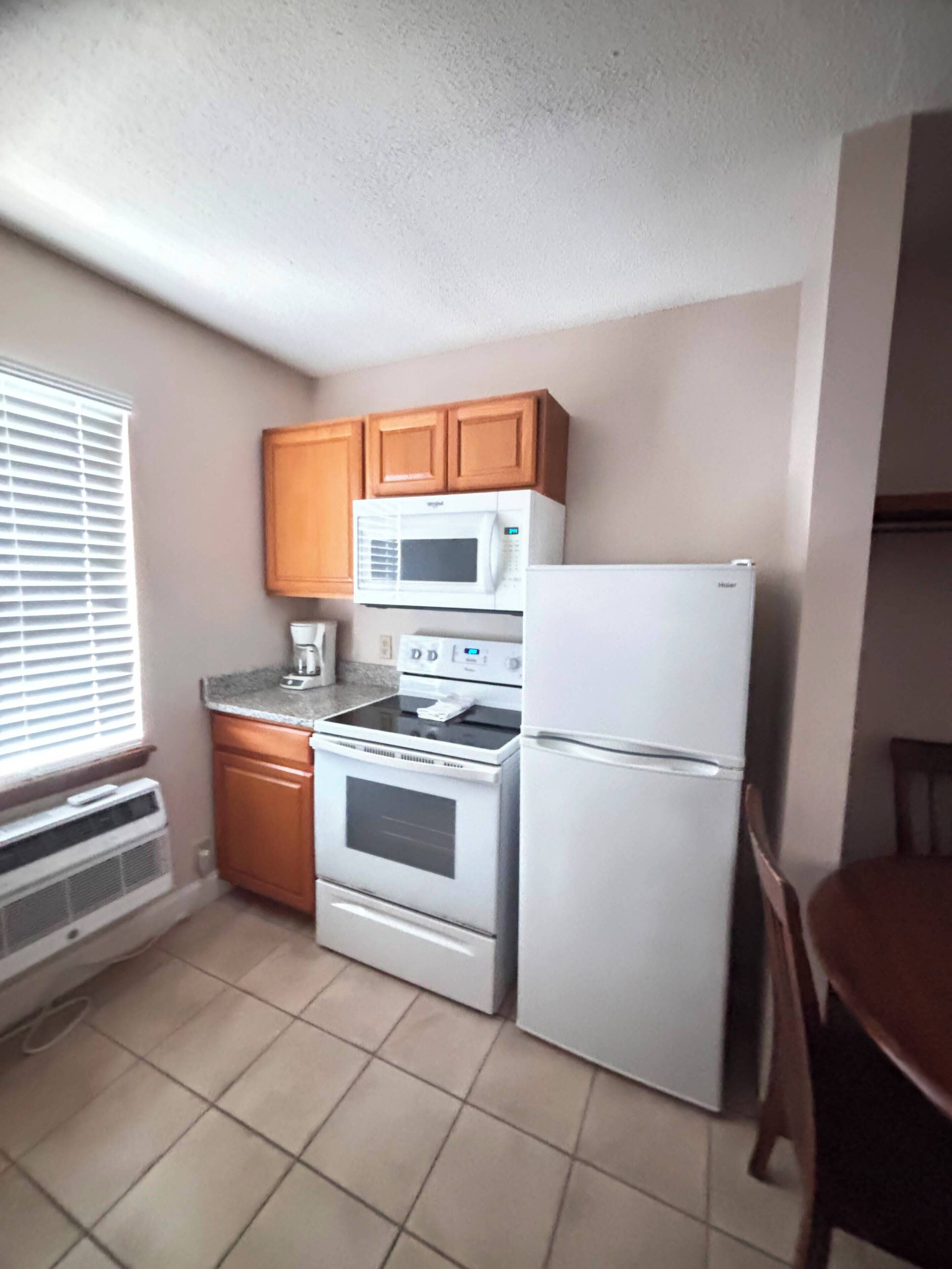 A compact kitchen with a refrigerator, microwave, stove, and oven.