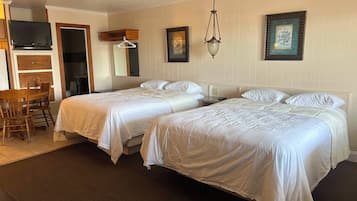 A hotel room with two beds, a desk with a chair, a television, and a framed picture on the wall.