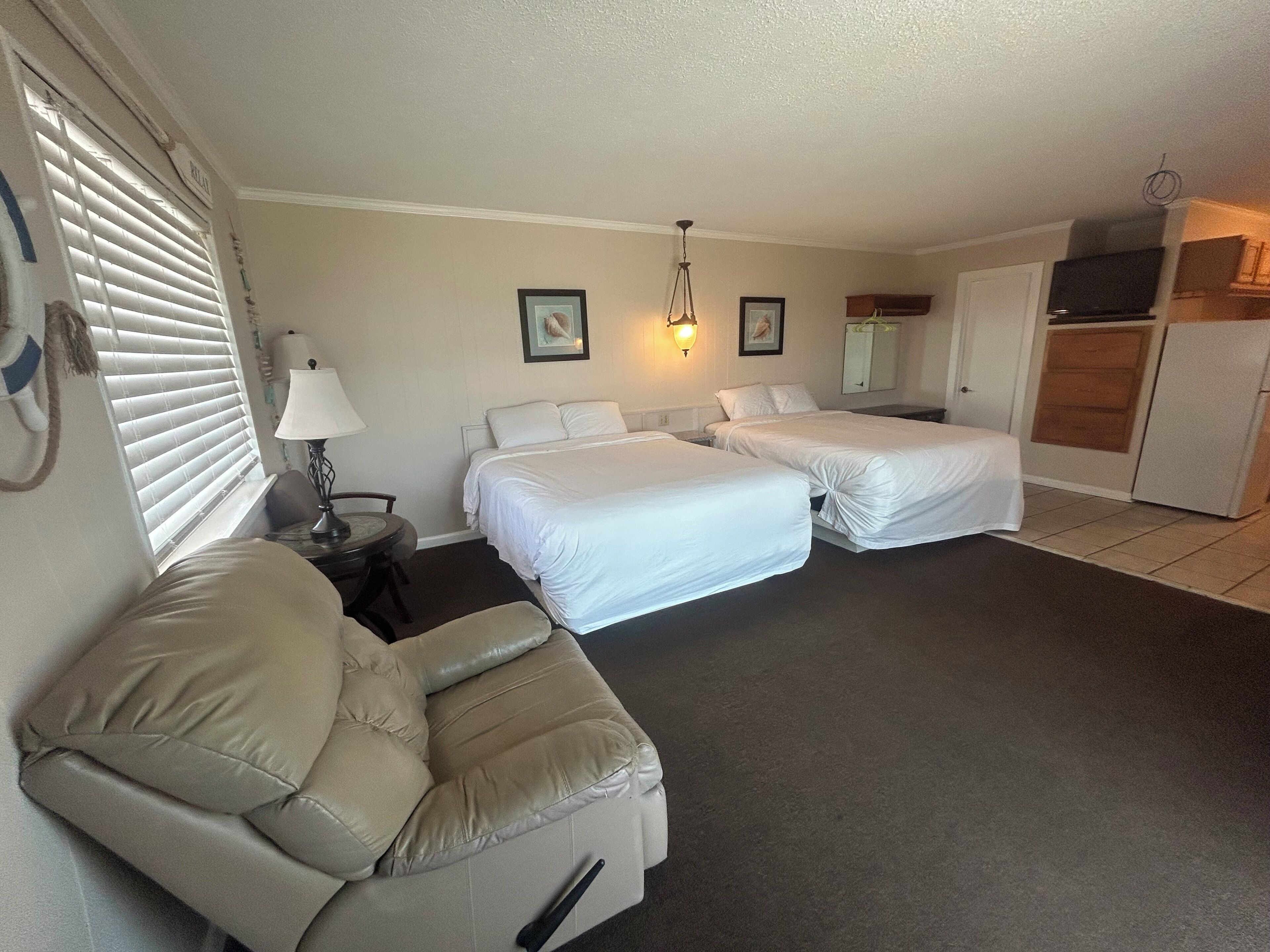 Une chambre d’hôtel avec deux lits, un canapé, un bureau et une kitchenette.