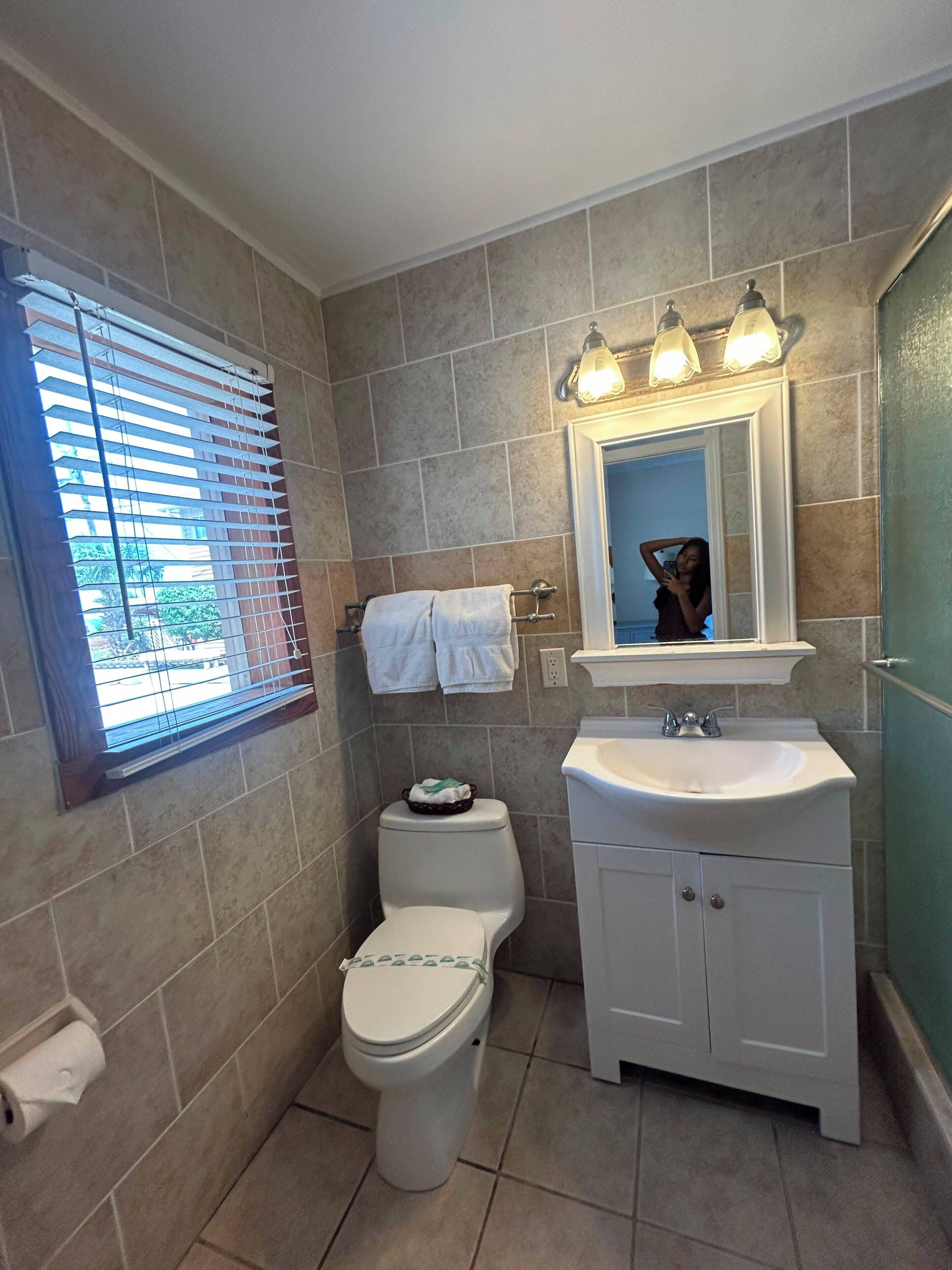 A bathroom with a toilet, sink, and mirror.