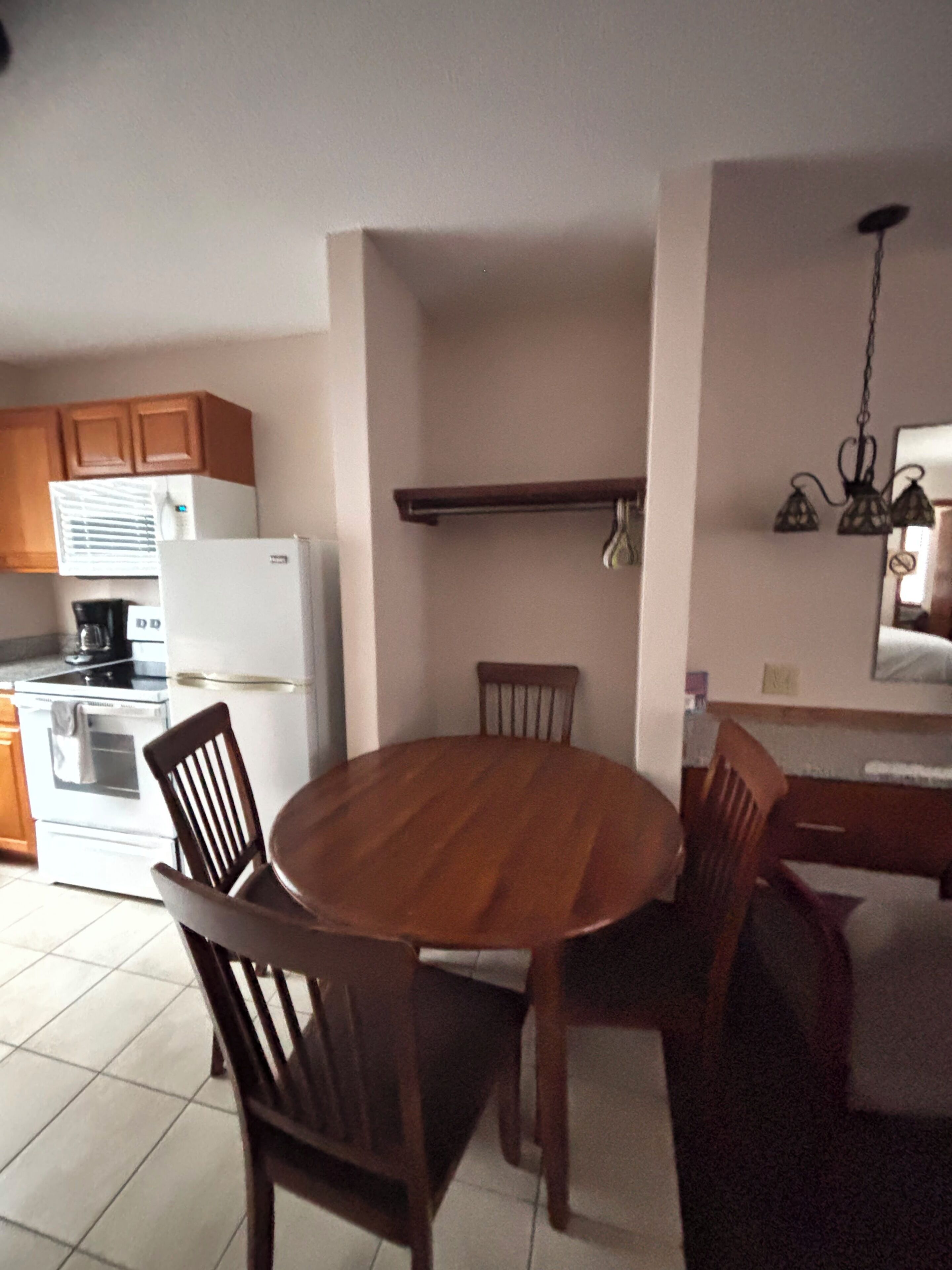 Una cocina con mesa y sillas, refrigerador, estufa y alacenas.